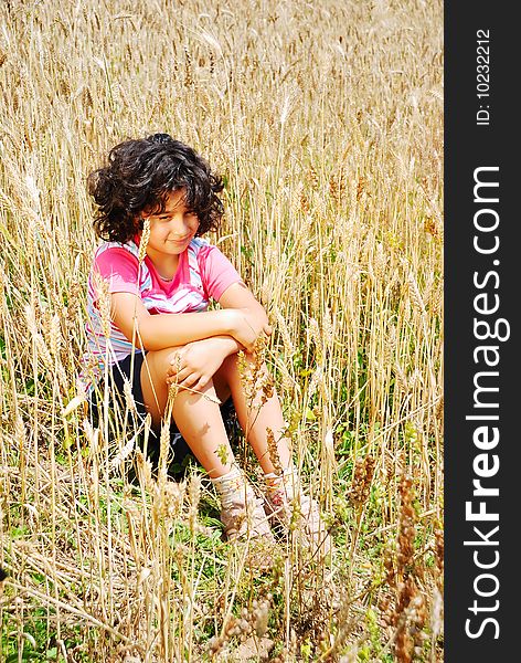 Little Pretty Girl Siting On Wheat Field