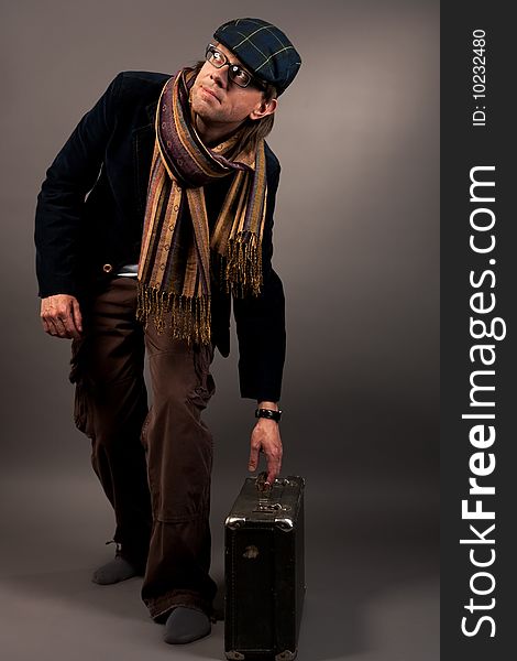 Young man in cap looking up with suitcase separated