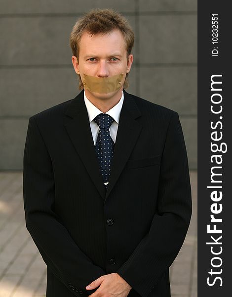 Businessman with adhesive on his Mouth on the street