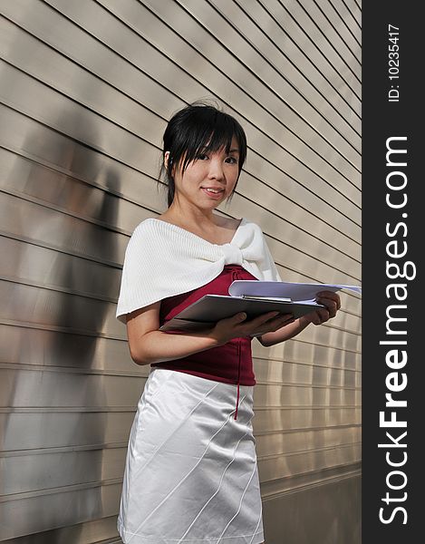 Beautiful young and modern Asian woman in the city showing a clipboard.