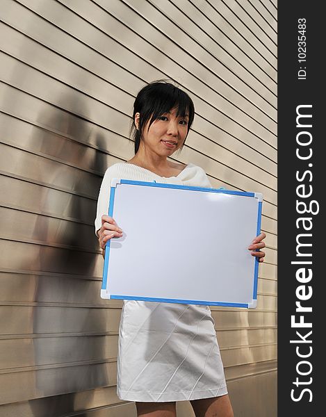 Beautiful young and modern Asian woman in the city showing a clipboard.
