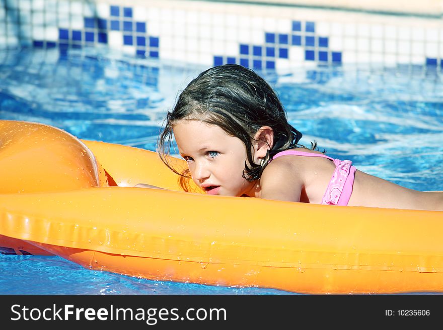 A young pretty girl relaxing on an orange airbed. A young pretty girl relaxing on an orange airbed