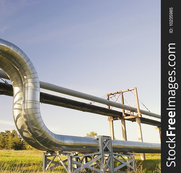 Industrial pipelines on pipe-bridge against blue sky.