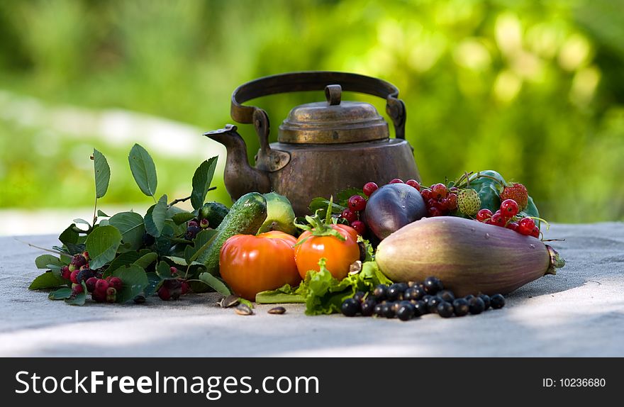 Berries, vegetables and an ancient teapot on a grey cloth. Berries, vegetables and an ancient teapot on a grey cloth