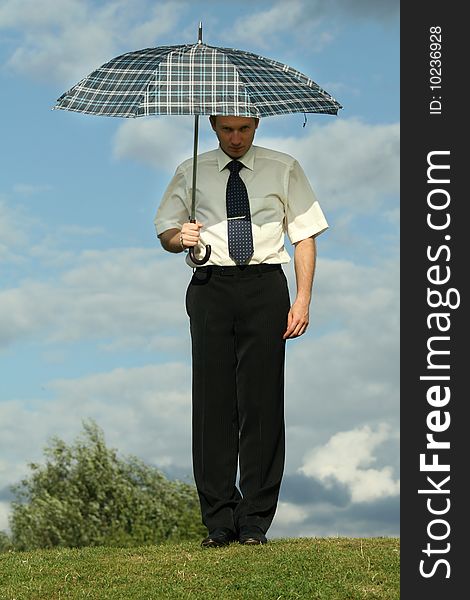 Seriously businessman holding umbrella on the grass. Seriously businessman holding umbrella on the grass