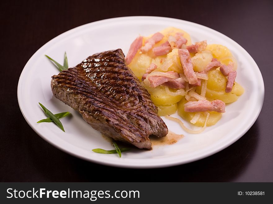 Steak with potatoes isolated on dark background