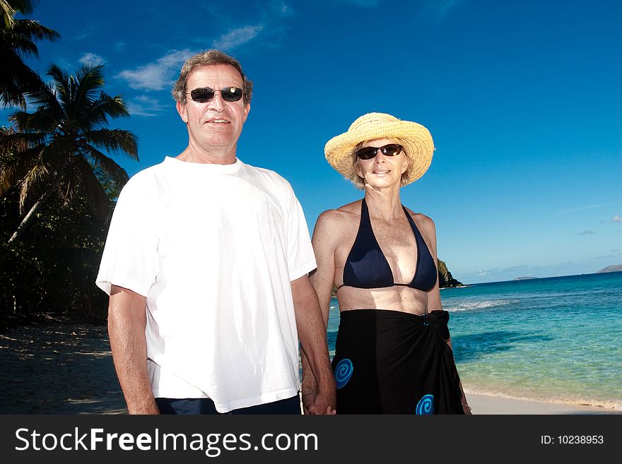 A happy mature couple poses on a tropical beach. A happy mature couple poses on a tropical beach
