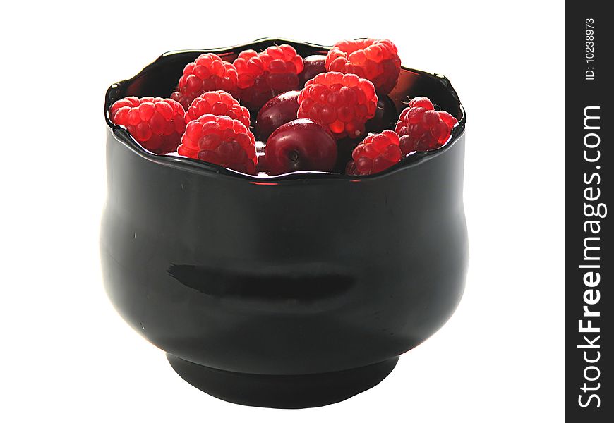 Raspberries and cherry in the black glass bowl, isolated on white. Raspberries and cherry in the black glass bowl, isolated on white