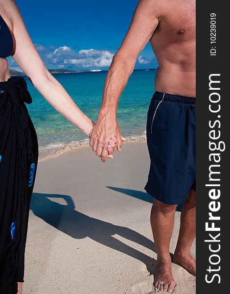 A couple holds hands on a tropical beach. A couple holds hands on a tropical beach
