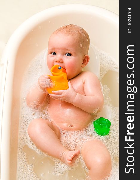 A baby-girl with a rubber-duck in her mouth. A baby-girl with a rubber-duck in her mouth