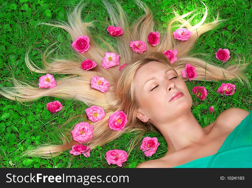 Beautiful woman relax on grass with flower all around head.
