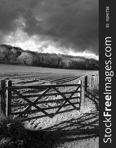 An old gate to ploughed field shadowed by a stormy skyline. An old gate to ploughed field shadowed by a stormy skyline