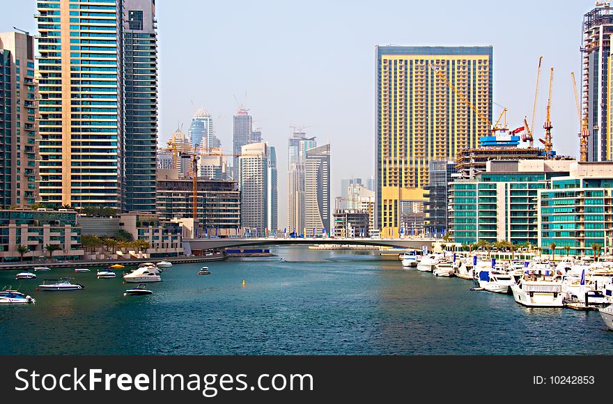 Several boats and yachts berthed in the Dubai Marina with luxury apartments in the background. Several boats and yachts berthed in the Dubai Marina with luxury apartments in the background