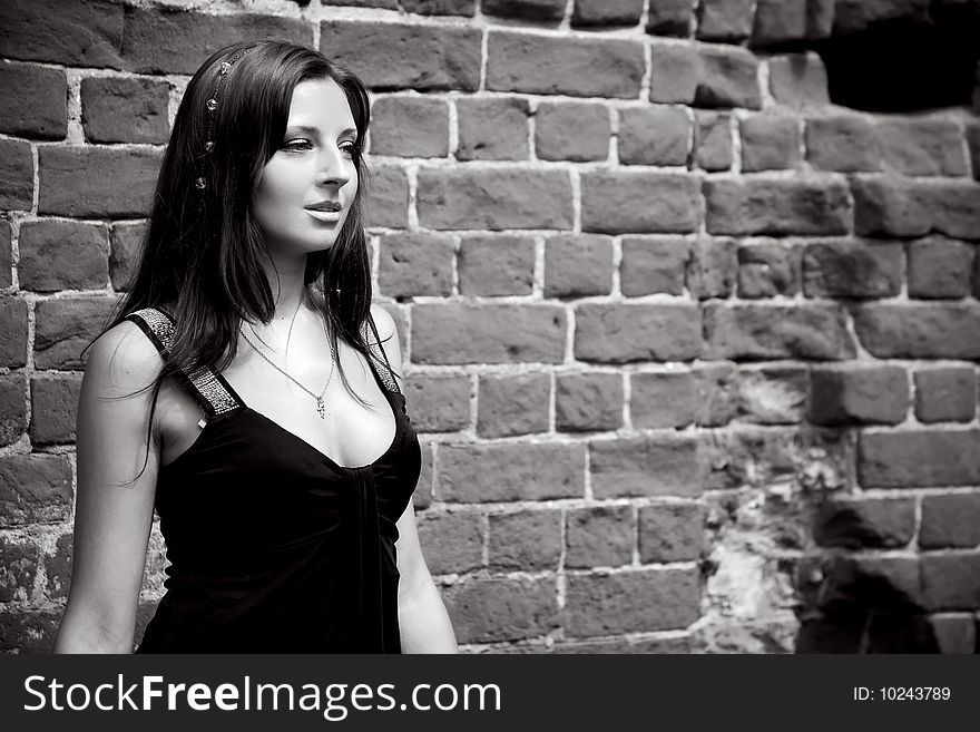 Woman near brick wall in black elegant black dress. Woman near brick wall in black elegant black dress