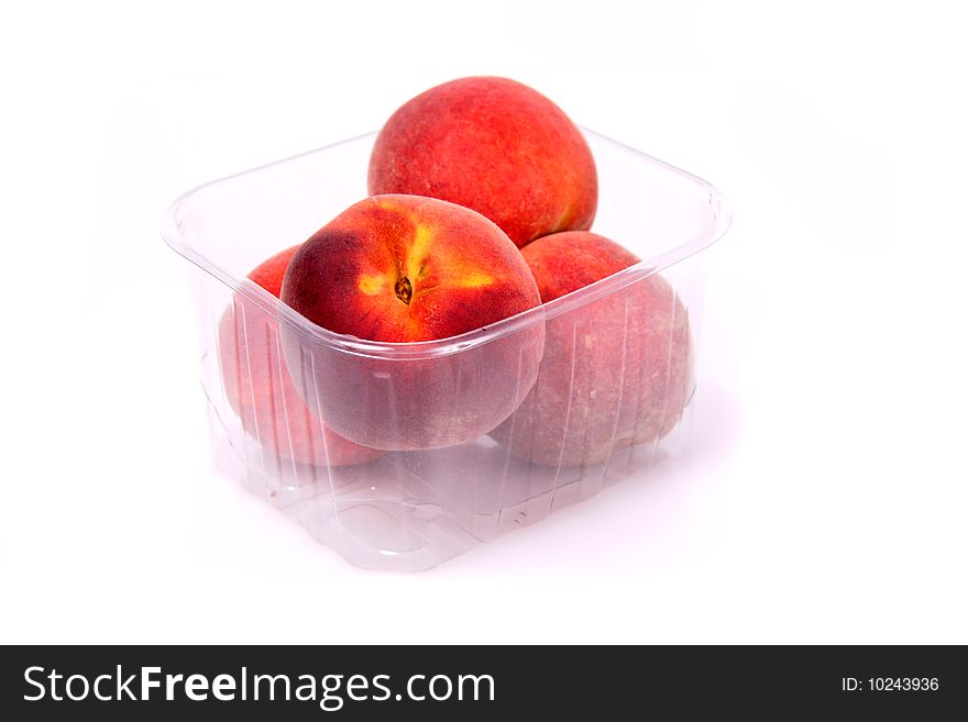 Four peaches in a plastic container on a white background. Four peaches in a plastic container on a white background.