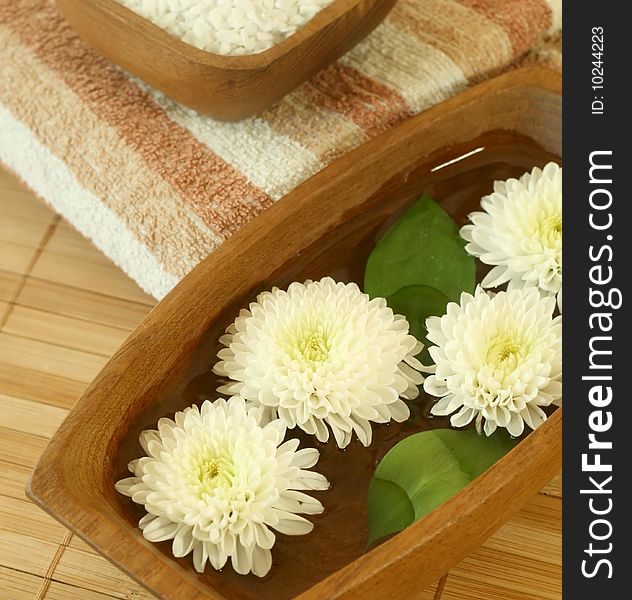 White flowers floating in wooden bowl. spa background.
