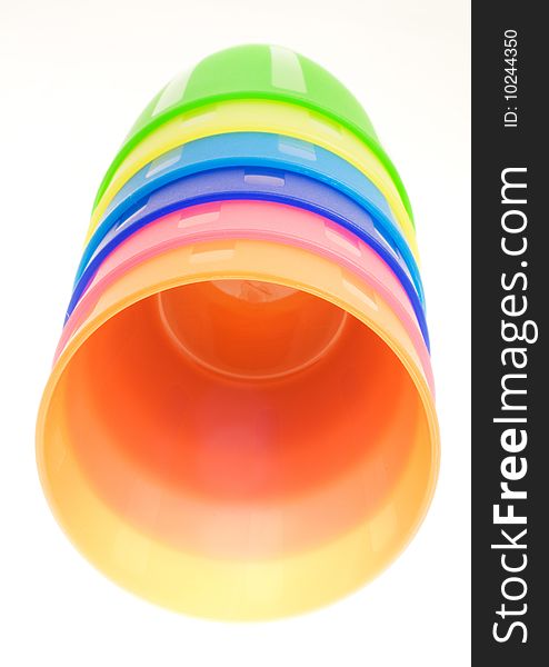 Stack of colored plastic cups lying on a white background.