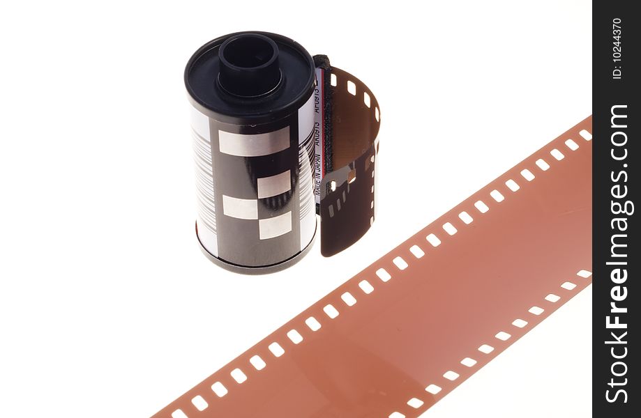 Photographic, 35mm, negative film in container, standing on a white background with a piece of negative film diagonally positioned in front. Photographic, 35mm, negative film in container, standing on a white background with a piece of negative film diagonally positioned in front.