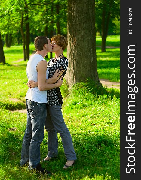 Teenagers: man is kissing girlfriend on nature. Full-length portrait. Teenagers: man is kissing girlfriend on nature. Full-length portrait