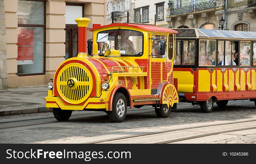 Yellow red excursion train with wagon in old town. Yellow red excursion train with wagon in old town