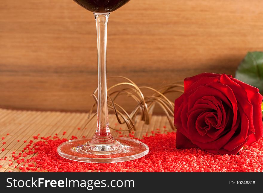 A red rose and a wine glass on a wooden bottom isolated on white background. A red rose and a wine glass on a wooden bottom isolated on white background