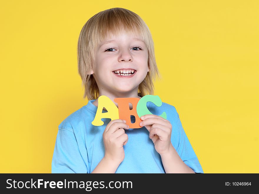 The small schoolboy with letters on a yellow background