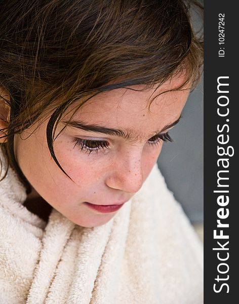 A wet young girl with a towel wrapped around her neck. ( After a bath or a swim.). A wet young girl with a towel wrapped around her neck. ( After a bath or a swim.)