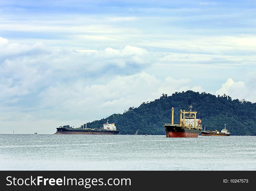 Few container ships sailing in the cloudy day.