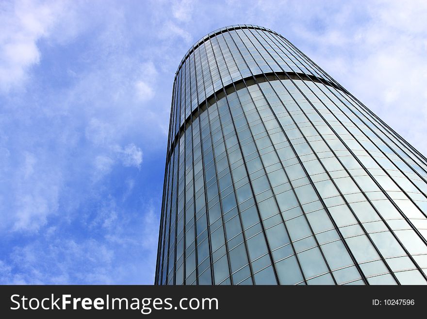 Perspective view of a skyscraper over cloudy blue sky.