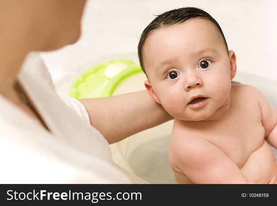 Baby boy in a bathtube held by his mother. Baby boy in a bathtube held by his mother