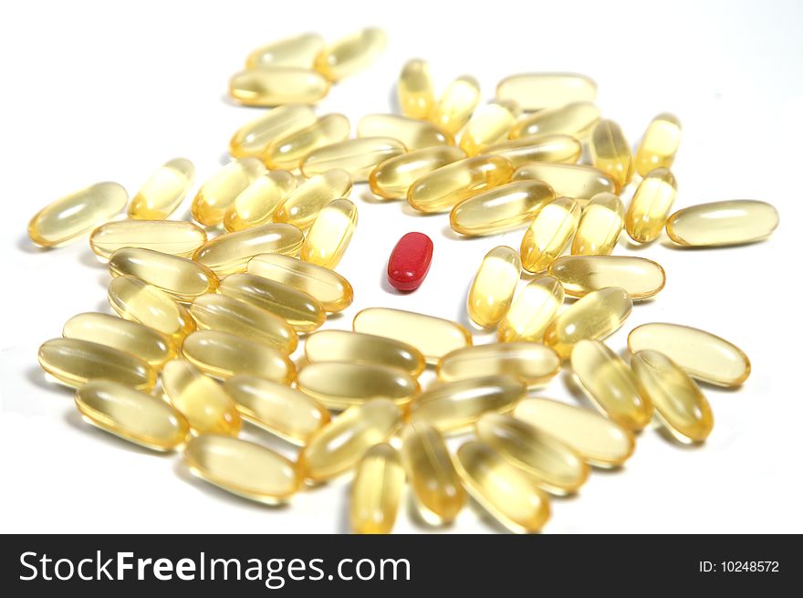 Clear gold pills on white with one red standout pill. Clear gold pills on white with one red standout pill