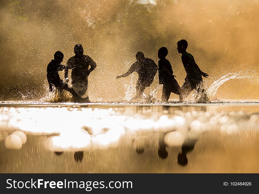 Boys Playfully Splashing Water On Each Other On Holiday.