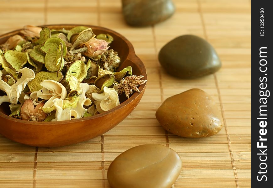 Natural herbal ingredient in wooden bowl and stones prepared for ultimate aromatherapy.