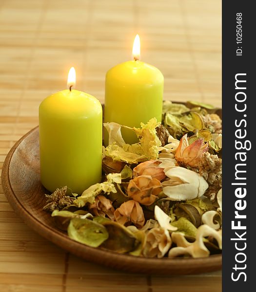Natural herbal ingredient in wooden bowl and two candles