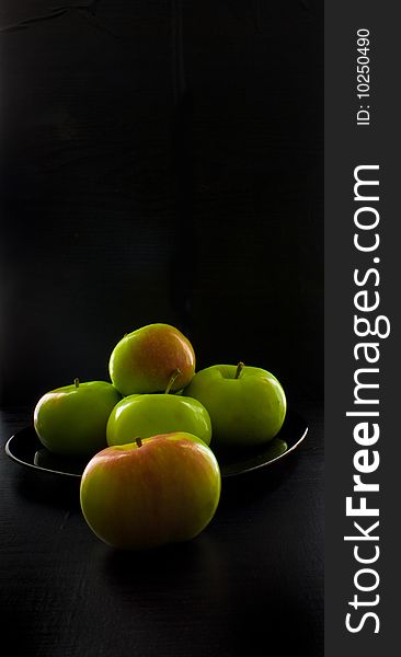 Apples in a black plate on a black background. Apples in a black plate on a black background