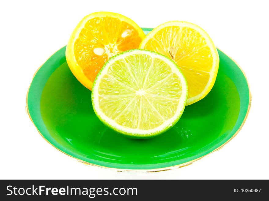 Lemon, lime and orange halves on a fancy green plate on a white background. Lemon, lime and orange halves on a fancy green plate on a white background