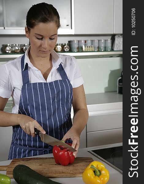 Young woman standing in the kitchen chopping pepper. Young woman standing in the kitchen chopping pepper