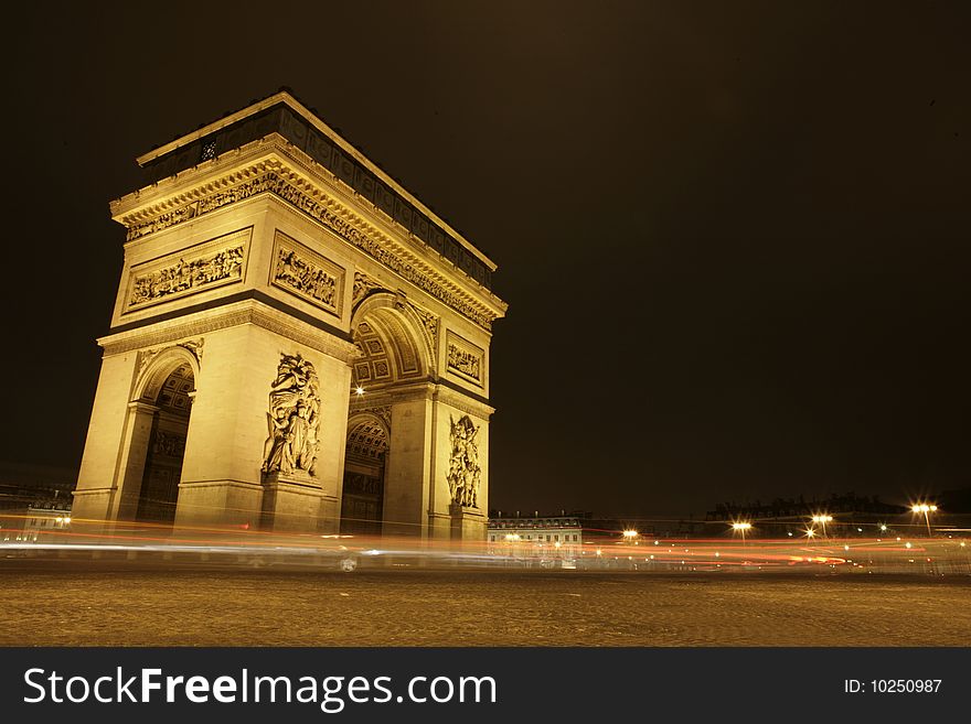 Arc de Triomphe at night with cars driving by