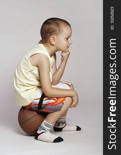 Child sitting on a ball and thinking. Child sitting on a ball and thinking