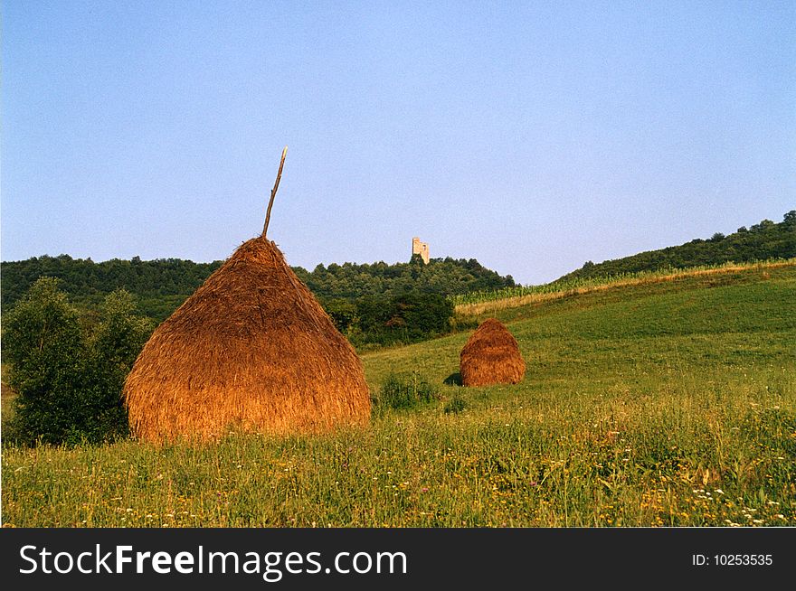 Castle ruin in background in Transsylvania with haystacks. Castle ruin in background in Transsylvania with haystacks