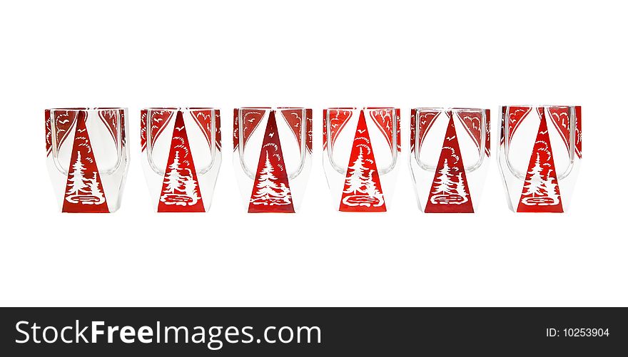 Row of beautiful red crystal liqueur glasses with cut fir-tree isolated. Row of beautiful red crystal liqueur glasses with cut fir-tree isolated