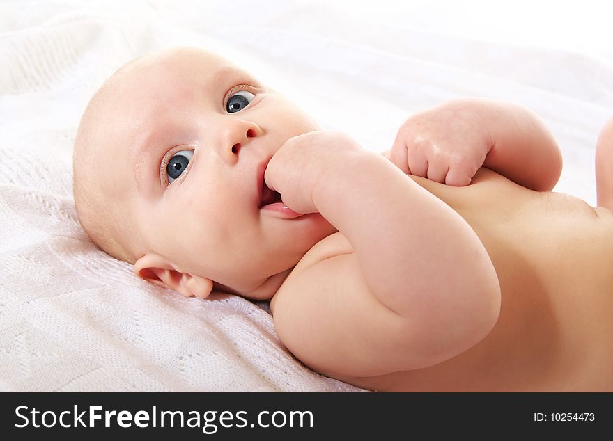 Cute baby boy on white blanket, close-up