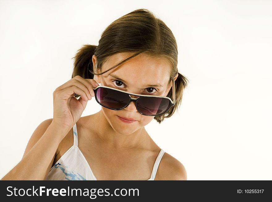 Young girl peering over large sunglasses, isolated on white background. Young girl peering over large sunglasses, isolated on white background