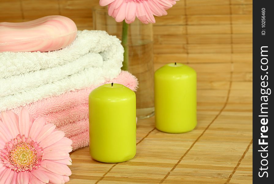 Towels, candles, soap and pink gerber.
