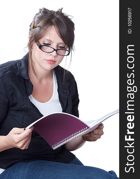 A young businesswoman in casual attire reviews her planner; isolated on a white background. A young businesswoman in casual attire reviews her planner; isolated on a white background.