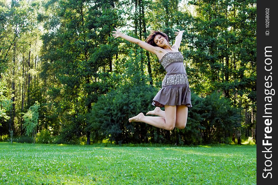 Smiling beautiful happy girl jumping in a park in summer. Smiling beautiful happy girl jumping in a park in summer