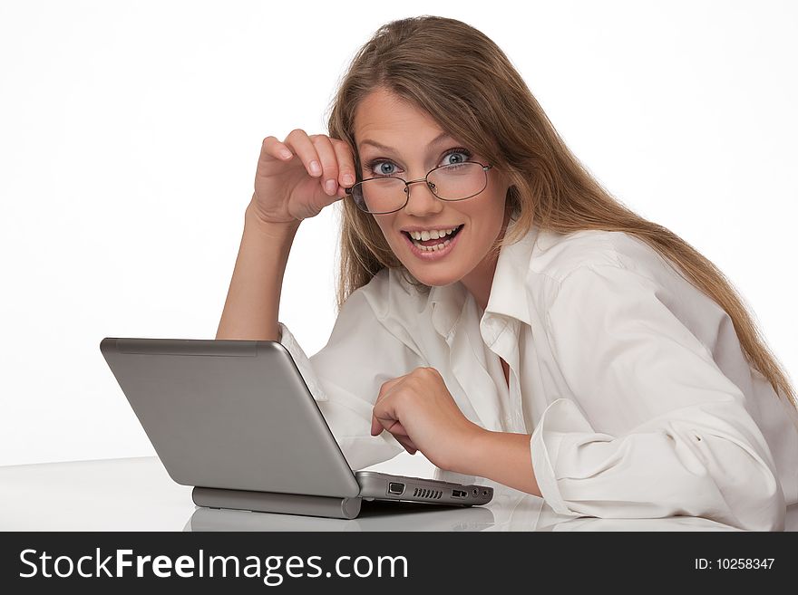 The modern young woman sits at a table with the personal computer, holds points in a hand and looks in the chamber. The modern young woman sits at a table with the personal computer, holds points in a hand and looks in the chamber