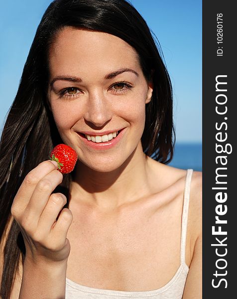 Woman eating fresh strawberry in the sun. Woman eating fresh strawberry in the sun