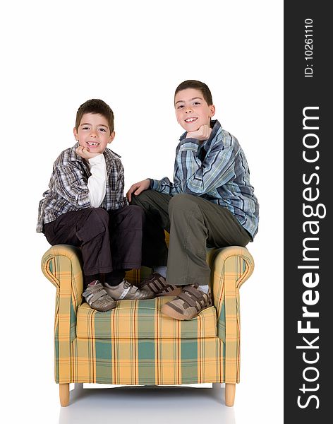 Two young happy smiling boys sitting on the back of the chair. Two young happy smiling boys sitting on the back of the chair