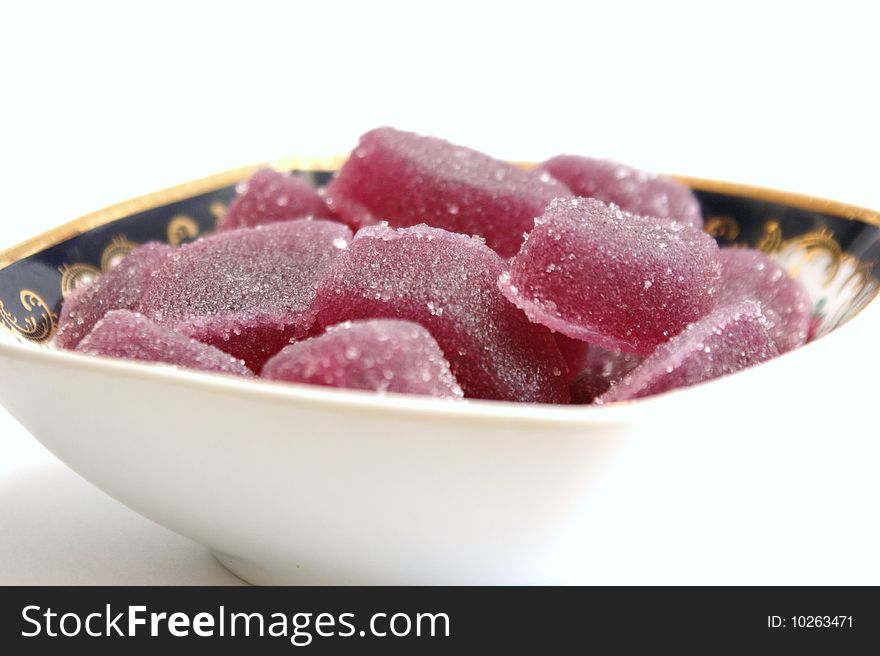 Fruit candy in a square plate with patterns on a white background